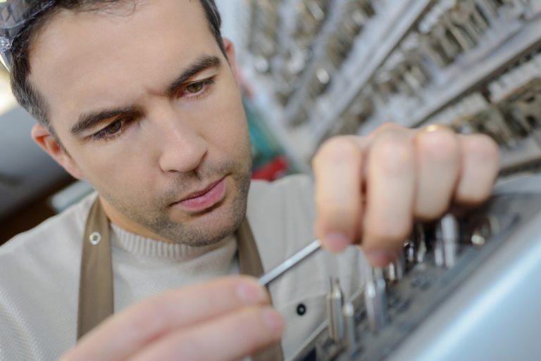 man in apron making duplicates of keys