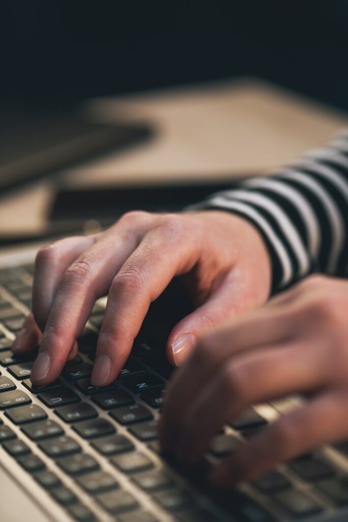 Female blogger typing blog post on laptop computer