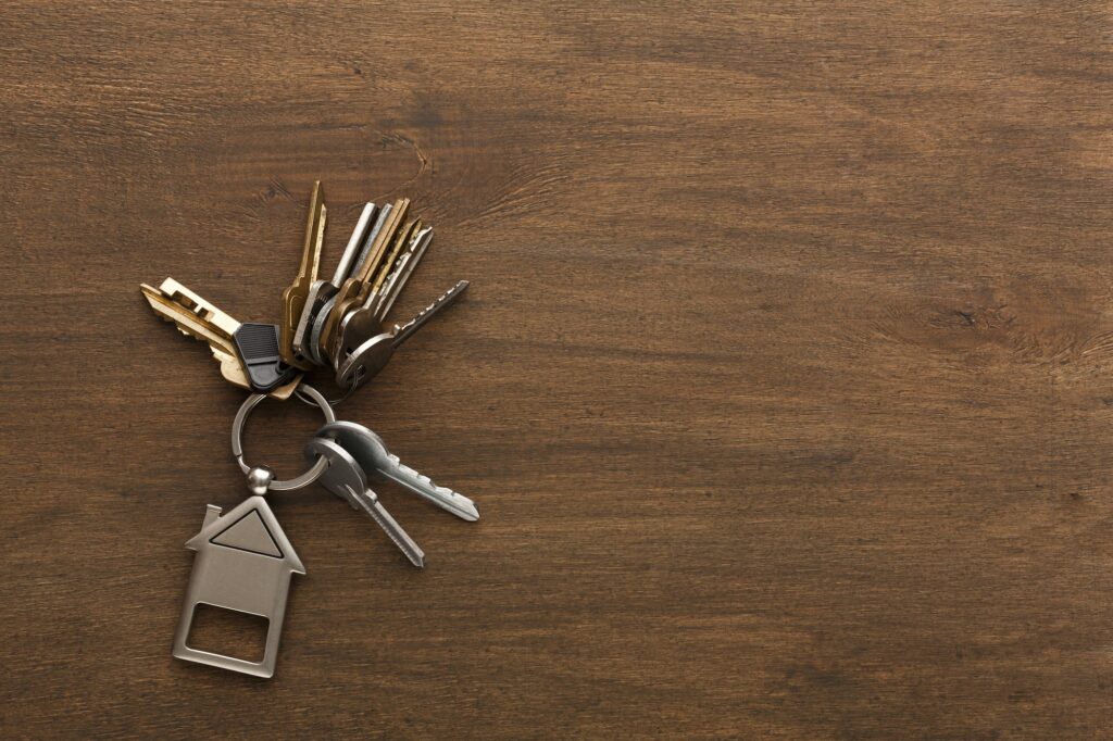 Bunch of keys with house shaped keychain on white wood