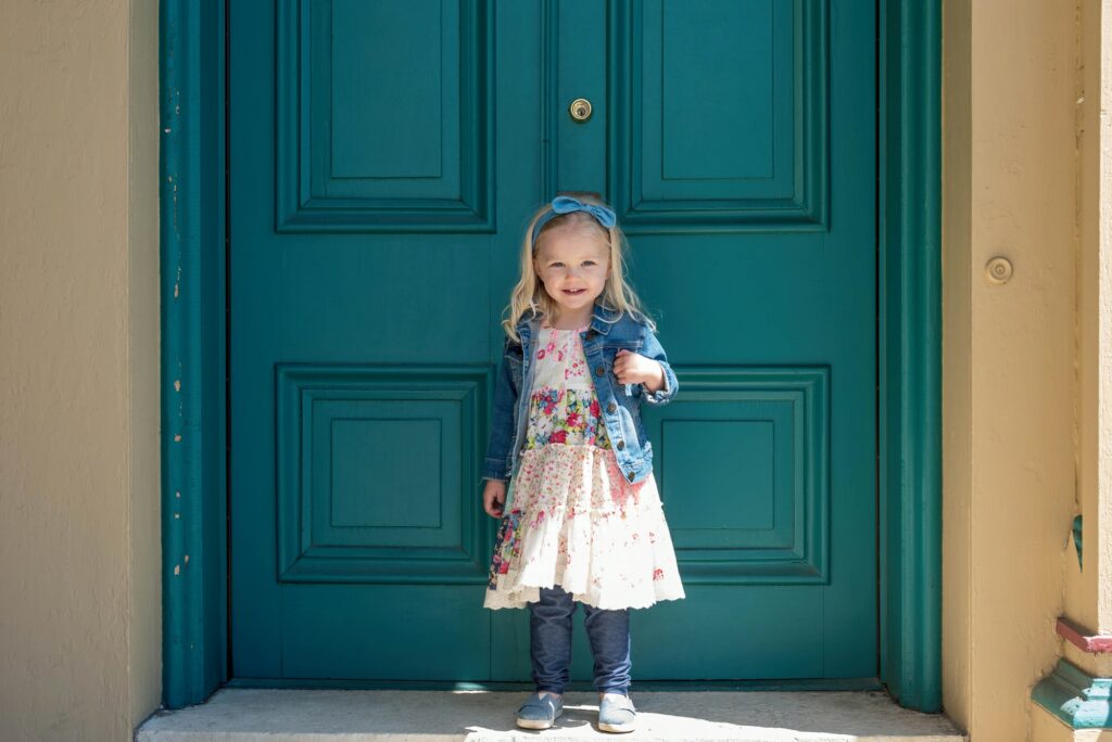 Little girl standing in front of painted doors
